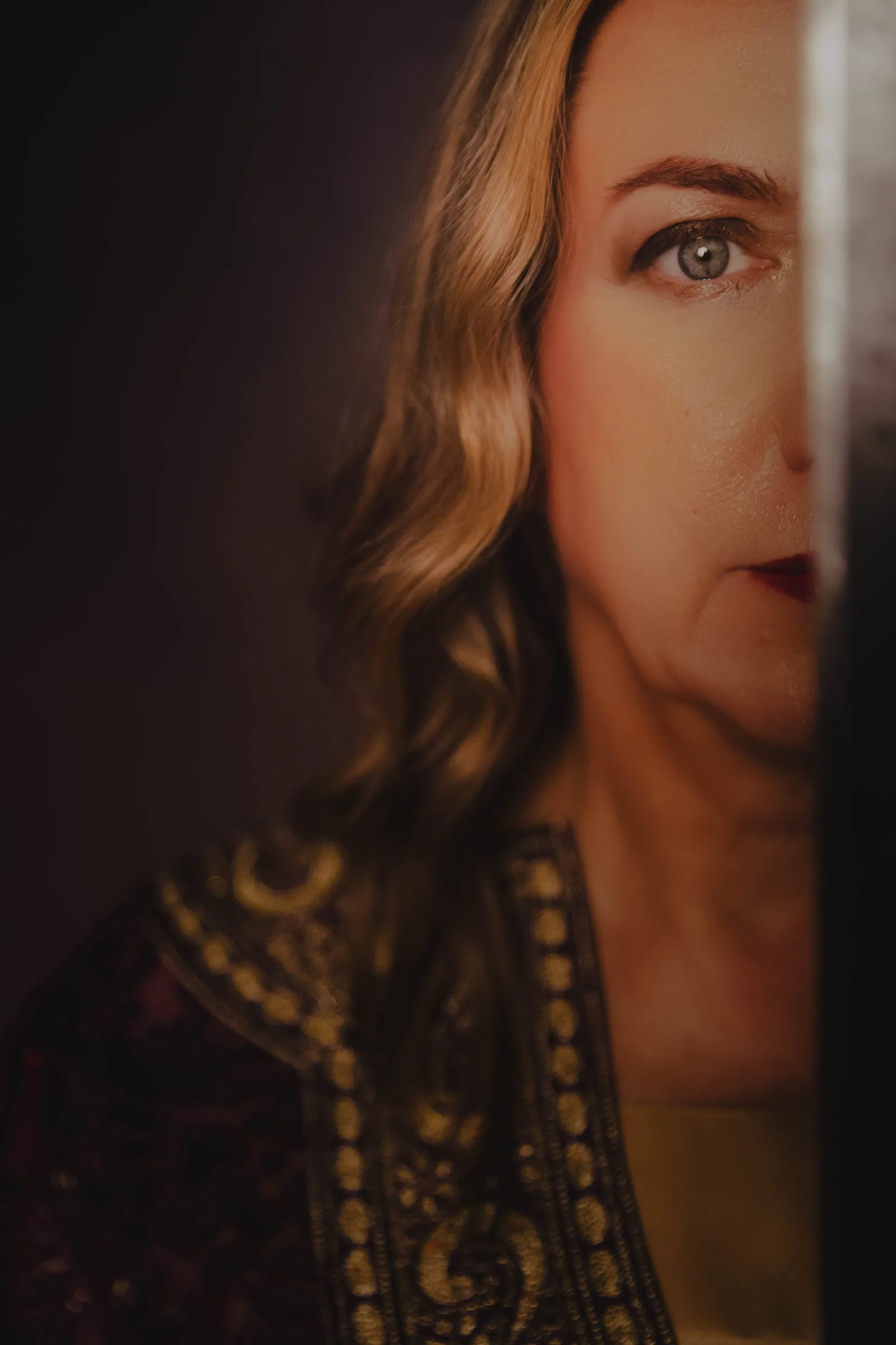 Sharon Day, half in shadow behind the blade of a ritual sword